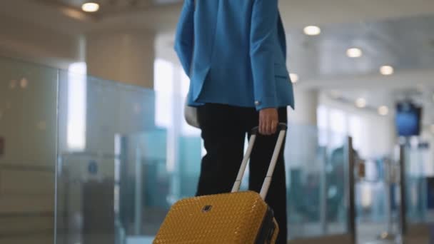 空港ターミナルを歩くスーツケースを持つ女性 バックビュー — ストック動画