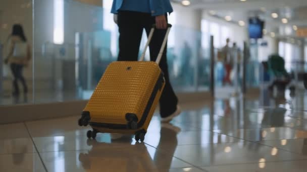 空港ターミナルを歩くスーツケースを持つ女性 バックビュー — ストック動画