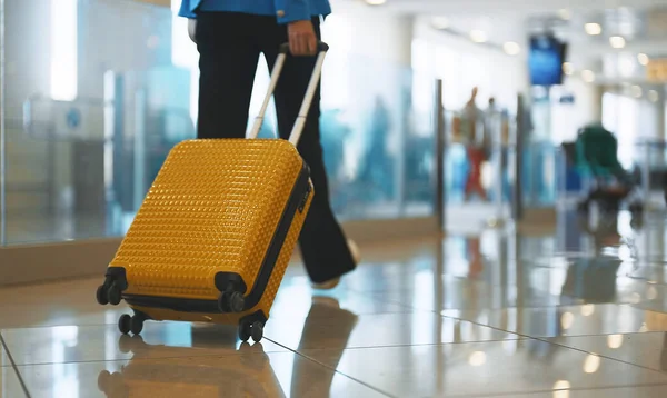 提着手提箱在机场候机楼行走的女人 背景色 — 图库照片