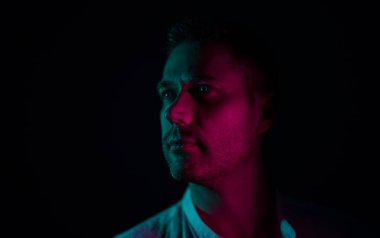 Tıraşsız, orta yaşlı yakışıklı bir adamın portresi. Neon ışıklarıyla.