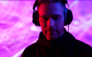 Kulaklıklı erkek DJ bir müzik kulübünde çalışıyor..