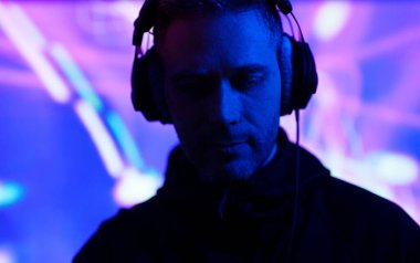 Kulaklıklı erkek DJ bir müzik kulübünde çalışıyor..