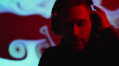 Kulaklıklı erkek DJ bir müzik kulübünde çalışıyor..