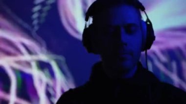 Kulaklıklı erkek DJ bir müzik kulübünde çalışıyor..