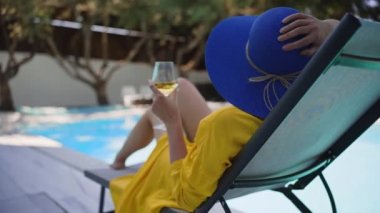 Yüzme havuzunun yanında dinlenen beyaz kadehli bir kadın..