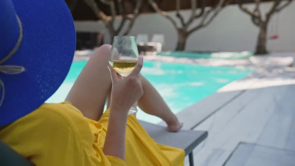 スイミングプールの近くでリラックスしたワインの白いグラスを持つ女性 — ストック動画
