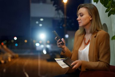 Bekleme salonunda pasaportu ve uçak bileti olan bir kadın var..