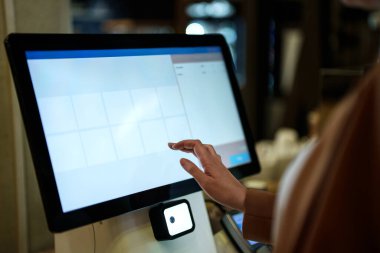 Woman pays at self-checkouts in supermarket.