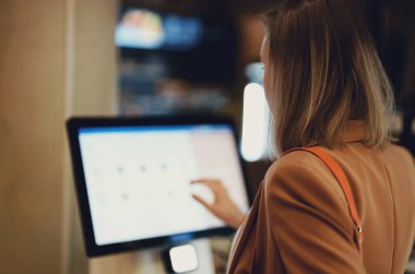 Woman pays at self-checkouts in supermarket.