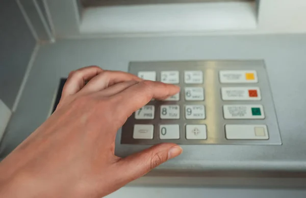 Woman enters a security PIN code at an ATM.