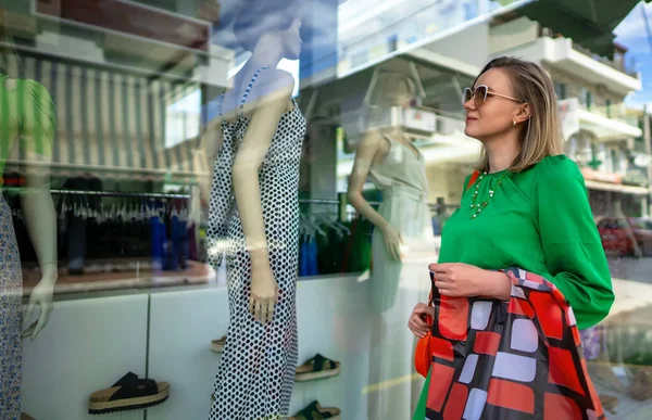 Woman looking at the shop window of clothing store.