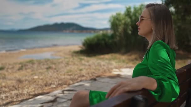 Γυναίκα Πράσινο Φόρεμα Κάθεται Ένα Παγκάκι Στην Παραλία — Αρχείο Βίντεο