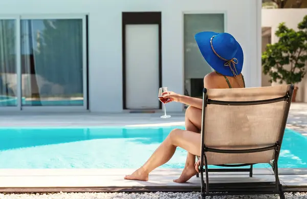 プールの近くでワインを一杯飲む女性 ロイヤリティフリーのストック画像