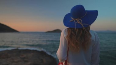 Deniz kenarındaki mavi şapkalı turist kadın..