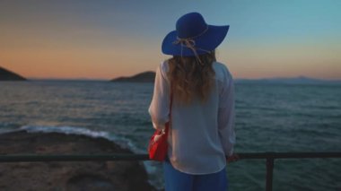 Deniz kenarındaki mavi şapkalı turist kadın..