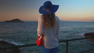 Deniz kenarındaki mavi şapkalı turist kadın..