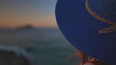 Deniz kenarındaki mavi şapkalı turist kadın..