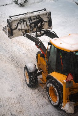 Sokakta kar kürekle traktör.