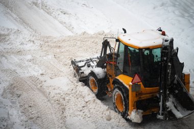 Tractor shoveling snow on the street. clipart