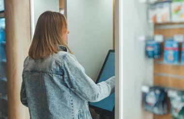 Kadın bir mağazada self servis terminali kullanıyor..