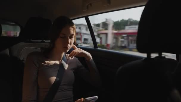 女の子はタクシーに乗って携帯電話を使用しています — ストック動画