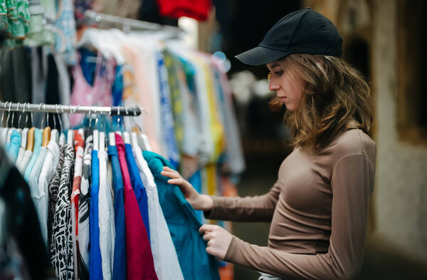 Teenage girl choosing a clothes at the evening bazaar.