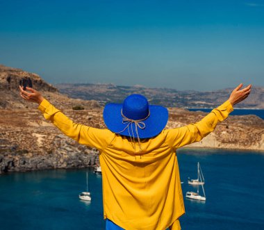 Denizde tatilde kolları açık bir kadın..