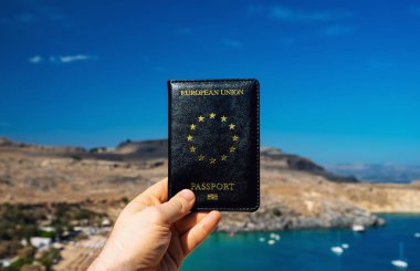 Tropik bir ülkenin arka planına karşı AB pasaportu elinde tutan adam.