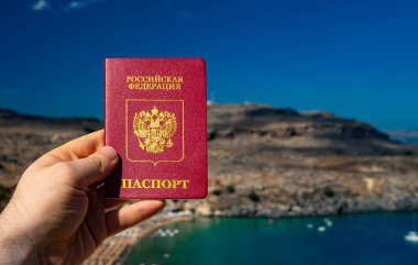 Tropikal bir ülkenin arka planında Rus pasaportu tutan adam..