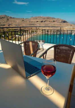 Laptop ve bir bardak şarap. Uzak çalışma için ideal bir yer.