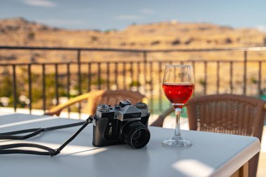 Masanın üzerinde retro kamera ve bir bardak kırmızı şarap var..