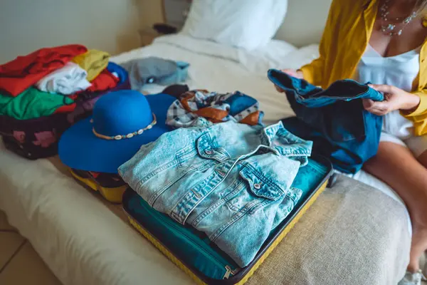 Woman packs her clothes into a suitcase. Preparing for vacation.