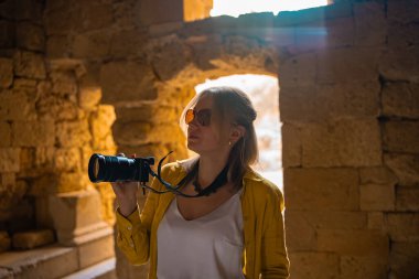 Eski bir tapınağın içinde kameralı bir kadın turist..