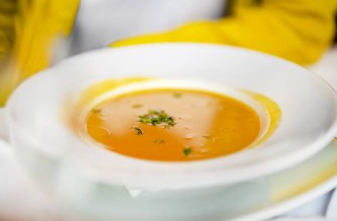 Bir kadın restoranda püre çorbası içiyor..