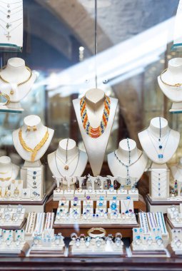 Bir mağazanın camında yüzükler, zincirler ve küpeler.