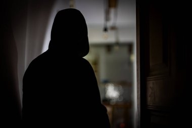 El feneri taşıyan maskeli soyguncu evini kontrol ediyor..