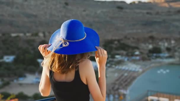 Dívka Modrém Klobouku Stojí Balkoně Dívá Pláž — Stock video