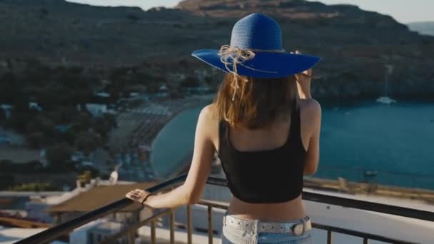 Fille Dans Chapeau Bleu Tient Sur Balcon Regarde Plage — Video