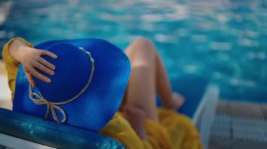 Mavi şapkalı kadın havuz kenarında dinleniyor..