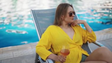 Şarabı olan güzel bir kadın havuzda dinleniyor..
