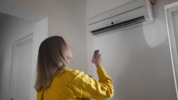 Kvinna Som Håller Fjärrkontrollen Syftar Till Luftkonditioneringen — Stockvideo
