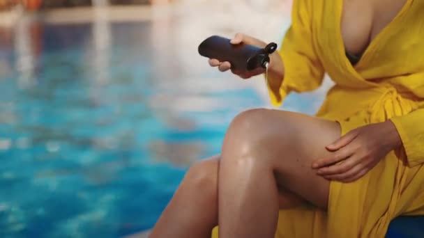 在游泳池附近的腿上涂防晒霜的女人 — 图库视频影像