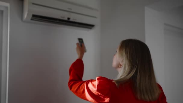Žena Červených Šatech Drží Dálkové Ovládání Zaměřené Klimatizaci Stock Video
