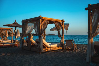 Plaj kabinleri ve güneş batarken deniz kenarında güneşlenirler..