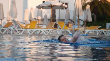 Açık havuzda yüzen bir adam..