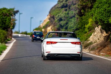 Beyaz Cabrio arabası yol boyunca gidiyor. Arka plan.
