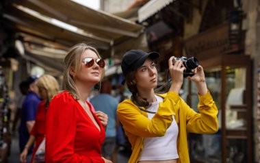 Kalabalık bir turistik şehirde iki turist fotoğraf çekiyor..