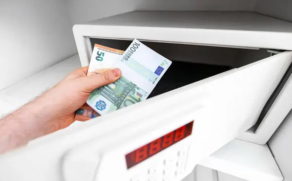 stock image Man puts or takes euro banknotes from a safe.