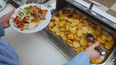 Bir kadın tabağına patates koyar..