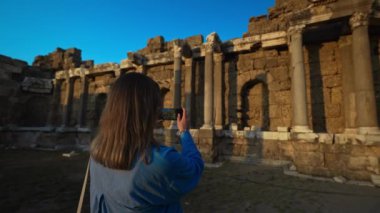 Kadın turist, antik bir şehrin kalıntılarının fotoğrafını çekiyor..